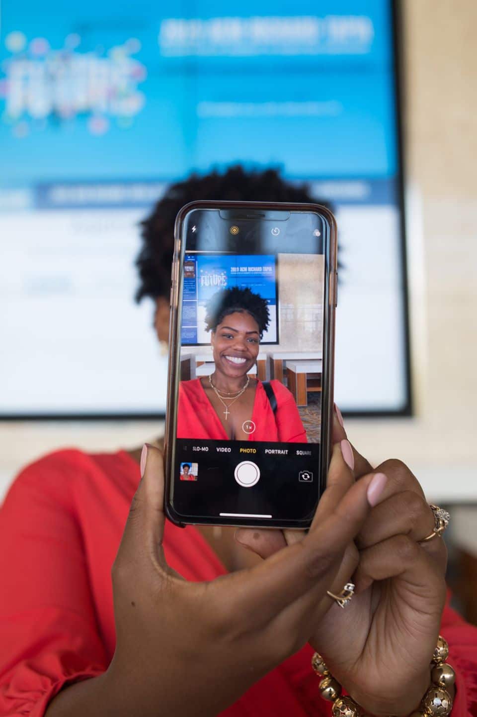 Lady taking a photo of herself with the front of the phone facing towards the camera